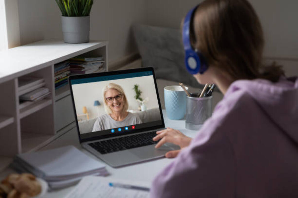 Il fenomeno mamme dal telefono - Distant lesson with middle-aged teacher. Adult grownup daughter or granddaughter talk with 60s grandmother use videocall, videoconference users, online meeting, over girl shoulder computer screen view