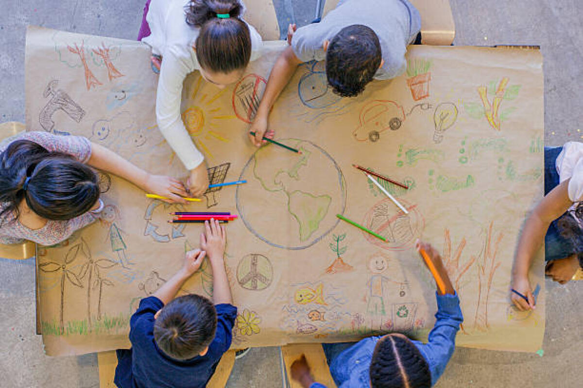 Appello di demA per la scuola, occorre unità d'intenti tra i diversi soggetti coinvolti: "Gli insegnanti, i dirigenti scolastici, il personale ATA, gli studenti e le loro famiglie" - An aerial view of a multi ethnic group of children learn about going green and color in environmentally friendly concepts surrounding a drawing of Earth.
