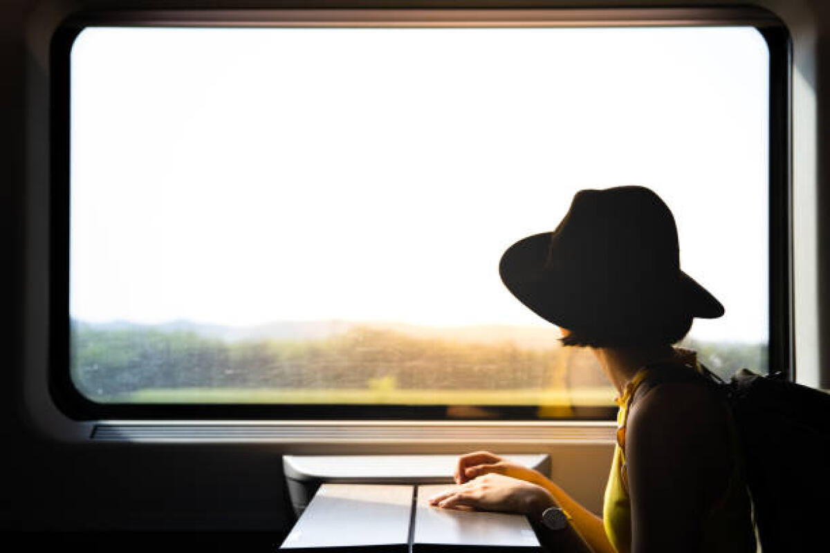 Scrivo dal treno perché non ho tempo per farlo altrove - A beautiful hipster asian woman traveling on the train. Sitting on the black leather cozy comfort seat in the business class of the train in Europe. Tourist travel concept.