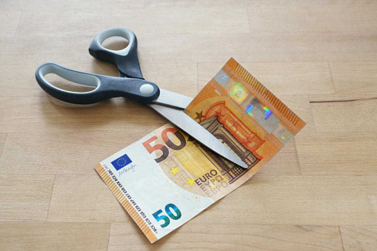 SBC hanno tagliato la carta del docente per pagare i boiardi di Stato e la negano a 200.000 supplenti annuali - Euro banknote is cut with scissors, business concept for German lower MwSt (value added tax), wage reduction and pay less money during coronavirus pandemic, wooden table, copy space