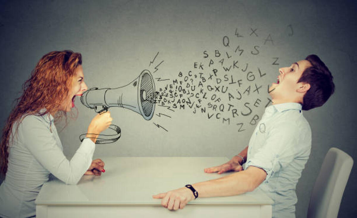 Diffamazione in ambito scolastico: quando le offese fra insegnanti, dirigente e genitori sono perseguibili - angry young woman with megaphone shouting at stressed scared man blown away by wave of alphabet letters