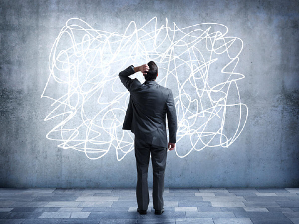 Docenti stremati sì, ma dalla burocrazia: il lato nascosto dello stress a scuola - A confused businessman stares at a scribble design that is painted on a wall. It represents the confusion and stress that some people feel in everyday life. He is looking up while standing with his back to the camera.