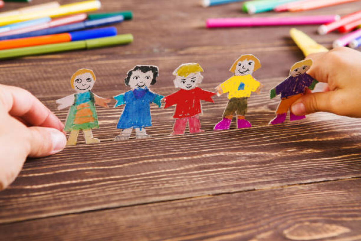 Inclusione sotto attacco? Un webinar per riflettere sullo stato dell'inclusione e del senso di partecipazione delle persone con disabilità in Italia - the child does figures of people of paper. Paper people on wooden background. Creative child play with craft.