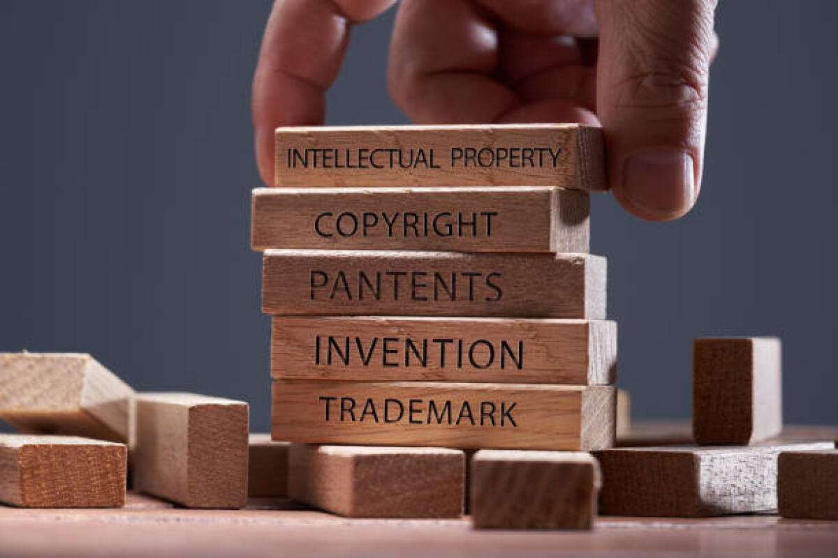 Iniziative per la Giornata internazionale della proprietà intellettuale 2025 - man adding a block showing the words Intellectual property on top of other wooden block with text copyright, patents, invention,and trademark