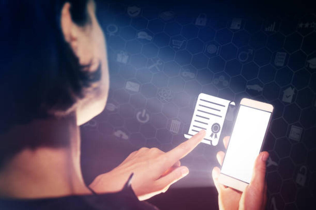 Scuola, certificazioni linguistiche, Gilda: bene MIM, primo passo per pulizia e trasparenza - Image of a girl with a smartphone in hands. She presses on the certificate (diploma) icon. Concept of online education.
