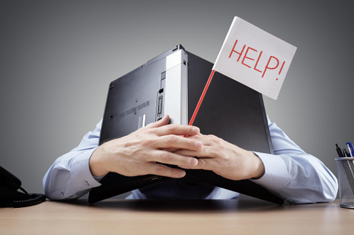 Continuità didattica sul sostegno, il sistema si inceppa: a pagare sono studenti fragili e famiglie - Frustrated and overworked businessman burying his head uner a laptop computer asking for help