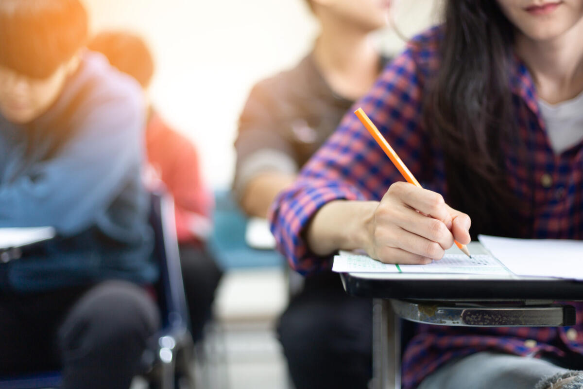 La scuola che vorrebbero gli studenti - high school,university student study.hands holding pencil writing paper answer sheet.sitting lecture chair taking final exam attending in examination classroom.concept scholarship for education abroad